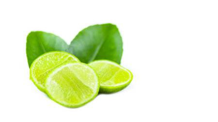Whole limes and lime halves placed on a white background, highlighting the freshness and vibrant color of the fruit.の写真素材