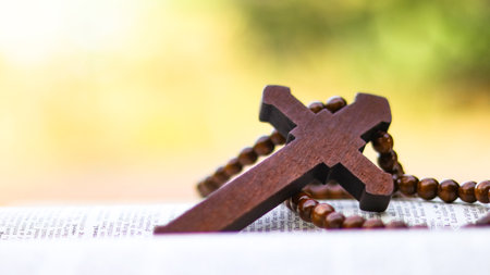 Brown wooden cross on an old open book symbolizing the spread of Jesus Christs love among Christians...
