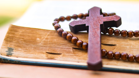 Brown wooden cross on an old open book symbolizing the spread of Jesus Christs love among Christians...