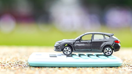 Model car and calculator are on the exposed aggregate concrete background. Planning of saving for...