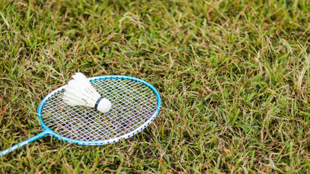 A badminton racket and shuttlecock resting on a grassy field, symbolizing the joy of outdoor sports, healthy living, and the importance of recreational activities to build fitness and bonds.の写真素材