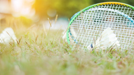 A badminton racket and shuttlecock resting on a grassy field, symbolizing the joy of outdoor sports, healthy living, and the importance of recreational activities to build fitness and bonds.の写真素材