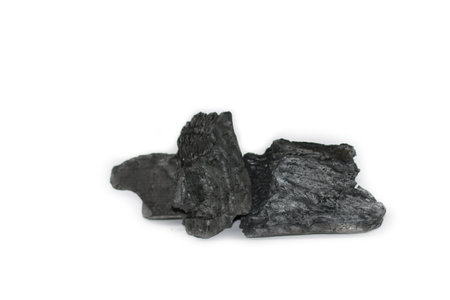 Isolated pieces of black charcoal resting on a clean white background, showcasing its rough texture and deep, rich color. Often used for grilling, art, and filtration, charcoal symbolizes both energy and transformation.の写真素材