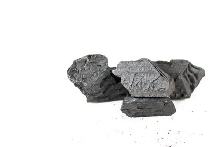 Isolated pieces of black charcoal resting on a clean white background, showcasing its rough texture and deep, rich color. Often used for grilling, art, and filtration, charcoal symbolizes both energy and transformation.の写真素材