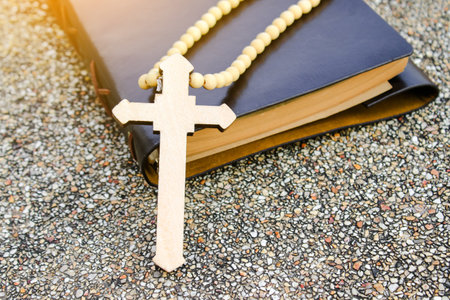 A white ivory cross placed on a dark brown notebook reflects purity, peace, and divine guidance. The contrast symbolizes light amidst darkness, faith, and personal devotion.の写真素材
