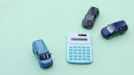 Small car models sit next to a calculator, symbolizing financial planning, insurance, budgeting, and car ownership. It represents vehicle costs, loans, and responsible investment.の写真素材