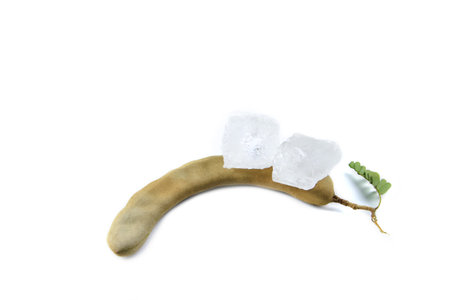 A chunk of alum is placed atop a ripe sour tamarind on a white background. This composition highlights the significance of natural elements in traditional medicine, cleansing, and food preparation.の写真素材