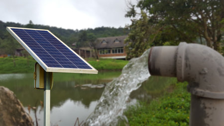 A solar panel installed to power a water pump, for residential area. Promoting sustainable living and renewable energy use.の写真素材