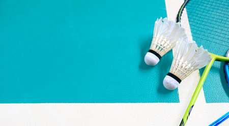 White badminton shuttlecocks and badminton rackets on green floor indoor badminton courtの写真素材
