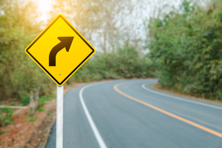 A right turn arrow with a blurred curved road in the background, safety direction and movement warn.