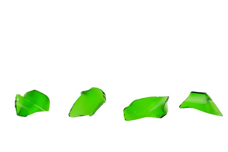 Sharp and jagged pieces of broken green glass cut out on a white background, symbolizing fragility...