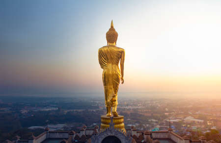 Golden buddha standing statue on a mountain Wat Phra That Khao Noi at sun rises, Nan Province, Thailandの写真素材