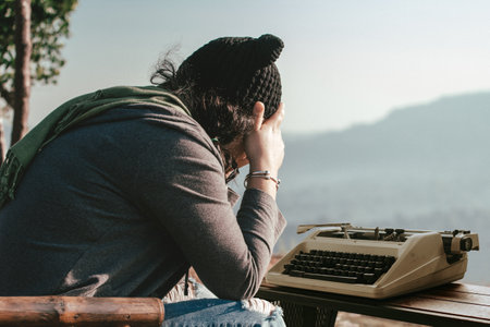 Stressed young woman writing with an old typewriter. She is tired from working.の写真素材