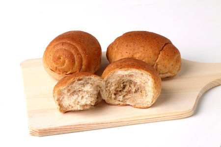 Freshly baked buns on a wooden cutting board on a white background