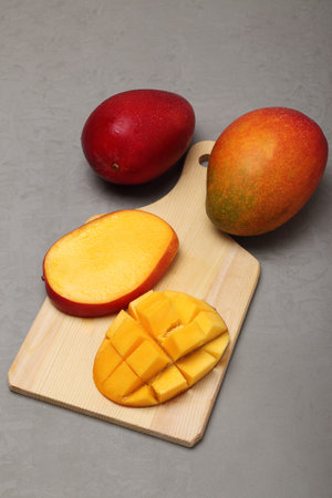 Mango fruit on a wooden cutting board on a gray background.の写真素材