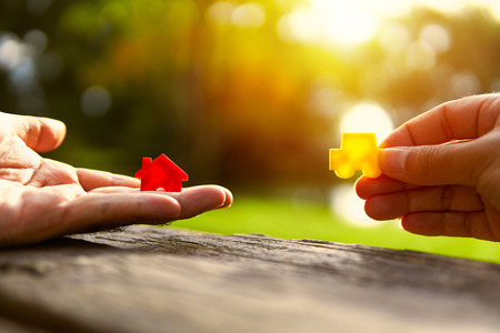 Left hand holding red and yellow model car holding.Have a solar background. Home loan with car exchange or trade in business or real estate.For family happiness.の写真素材