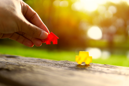 Left hand holding red and yellow model car holding on wood table.Have a solar background. Home loan with car exchange or trade in business or real estate.For family happiness.の写真素材