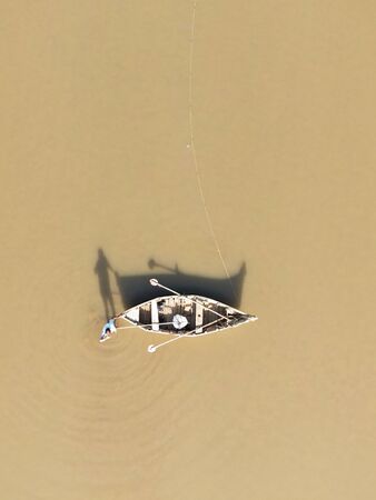 Aerial view of a fisherman with his boat in between the river. Shadow play of a fisherman with his boat. Drone view of a boat.の写真素材