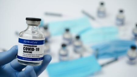 Covid-19 Corona Virus 2019-ncov Vaccine vials medicine drug ampoule bottle closeup syringe injection medical nitrile gloves mask glasses. Vaccination, treatment to cure Covid 19 Corona Virus infectionの写真素材