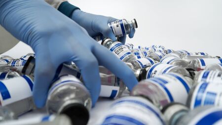 Covid-19 Corona Virus 2019-ncov vaccine vials medicine drug bottles syringe injection blue nitrile surgical gloves. Vaccination, immunization, treatment to cure Covid 19 Corona Virus infection Conceptの写真素材