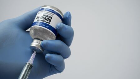 Covid-19 Corona Virus 2019-ncov vaccine vials medicine drug bottles syringe injection blue nitrile surgical gloves. Vaccination, immunization, treatment to cure Covid 19 Corona Virus infection Conceptの写真素材