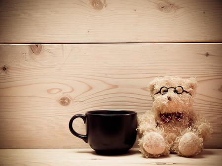 Coffee with teddy bear , The background is a brown wooden plate. (vintage) (picture with space for text)の写真素材