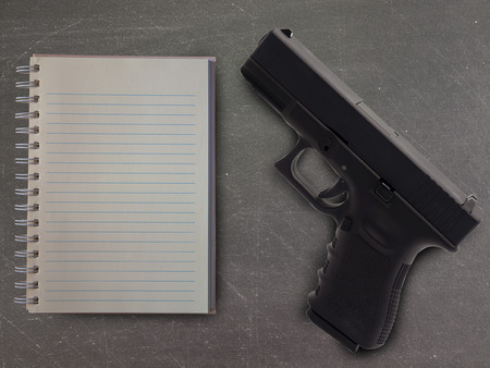 Top view notebook and gun on table  In school. (prevention concept)の写真素材