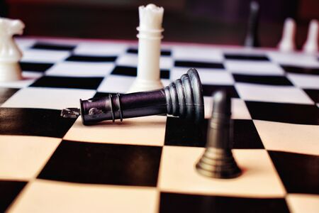 Chess game ongoing on a chess board . the black king fall down on the board.の写真素材