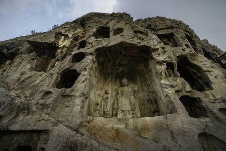 Buddha in a small cave on west hill limestone cliff. Longmen Grottoes Luoyang, Henan province, Chinaの写真素材