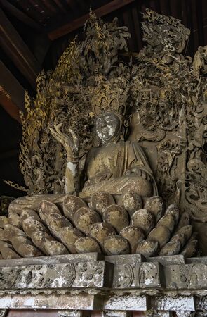 Old statue of buddha in ancient altar with carved details in wood. Altar figure located in Shuanglin Temple (or Zhongdu Temple), outskirts Pingyao Old City, Shanxi province, Chinaの写真素材