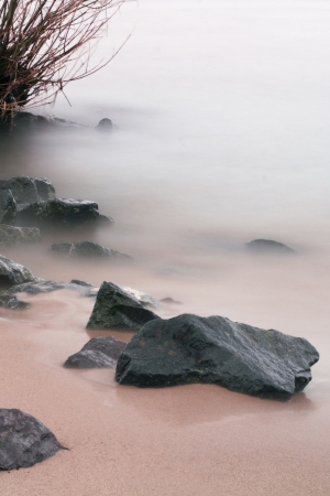 rocks on the beach by a mystic fog surroundetの写真素材