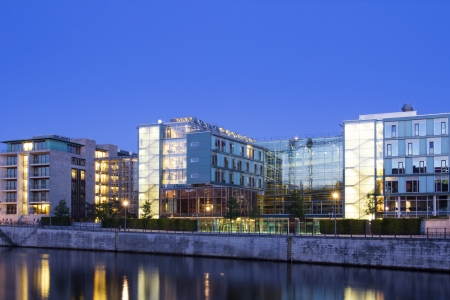 Modern office and apartment buildings on a canal, illuminated during the twilight hour の写真素材