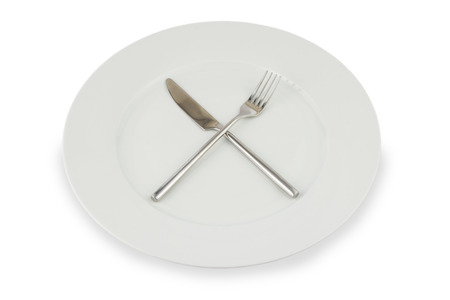silver knife and fork crossed on a white plateの写真素材