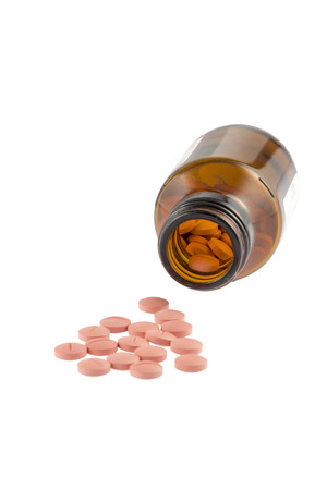 Red Pills in and in front of a brown bottle isolated on white の写真素材