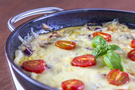 Omelette with tomatoes cheese and fresh basil on wooden tableの写真素材