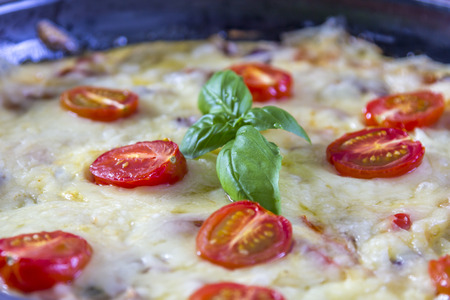 Omelette with tomatoes cheese and fresh basil on wooden tableの写真素材