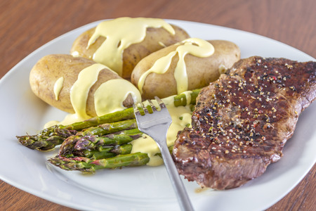 Green Asparagus with potatoes, beef and hollandaise sauce on a white plateの写真素材