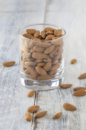 almonds in a glass on a wooden tableの写真素材
