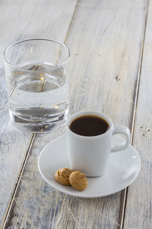 A Cup of espresso with italian amarettini cookies on a wooden table. Traditionally served with a glass of water. の写真素材