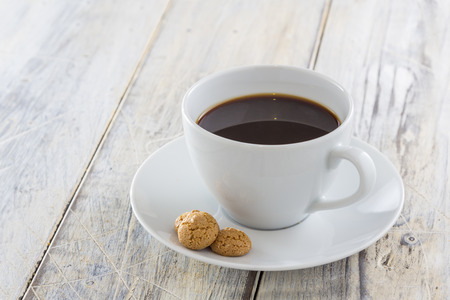 A Cup of coffee with traditional italian amarettini cookies on a wooden tableの写真素材