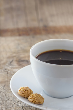 A Cup of coffee with traditional italian amarettini cookies on a wooden tableの写真素材