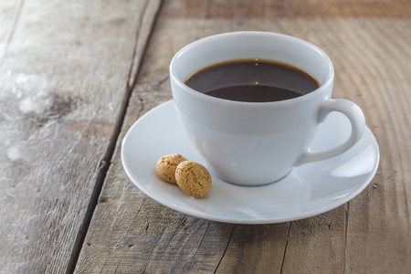 A Cup of coffee with traditional italian amarettini cookies on a wooden tableの写真素材