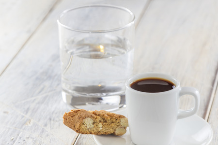 A Cup of espresso with italian biscotti cookies on a wooden table  Traditionally served with a glass of water の写真素材