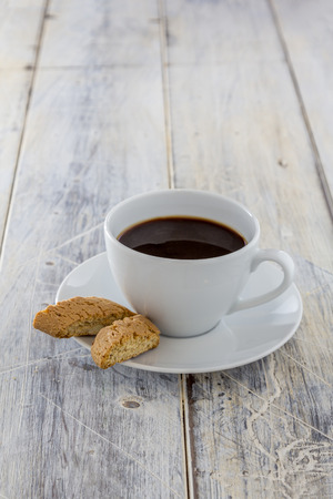 Traditional italian biscotti cookies with a cup of coffee on a wooden tableの写真素材