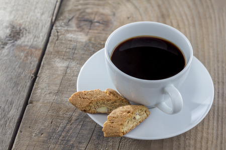 Traditional italian biscotti cookies with a cup of coffee on a wooden tableの写真素材