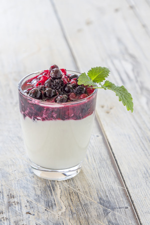 Yoghurt with red Berries in a glass on a wooden tableの写真素材