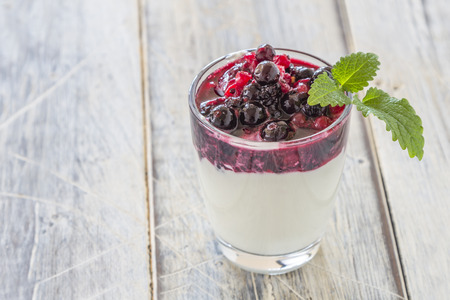 Yoghurt with red Berries in a glass on a wooden tableの写真素材