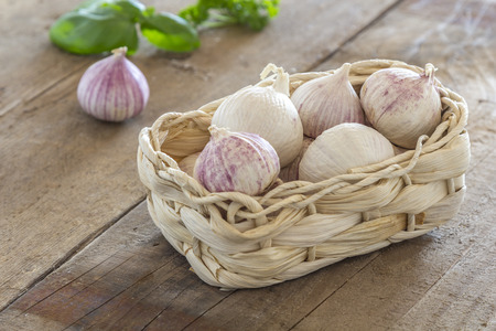 Garlic cloves in a small Basket on a wooden tableの写真素材