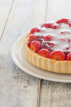 Homemade strawberry cake on a white platter on a wooden tableの写真素材