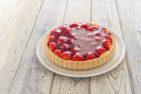 Homemade strawberry cake on a white platter on a wooden tableの写真素材